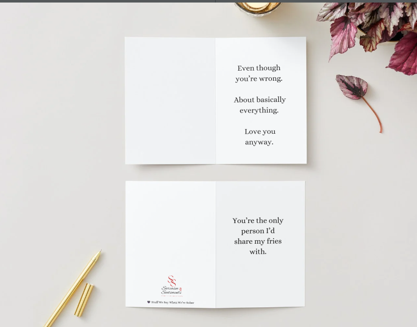 Two greeting cards with humorous text on a light surface with decorative elements.